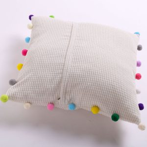 white pillow with pom poms