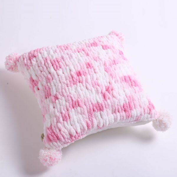 pink and white pillow with pom poms